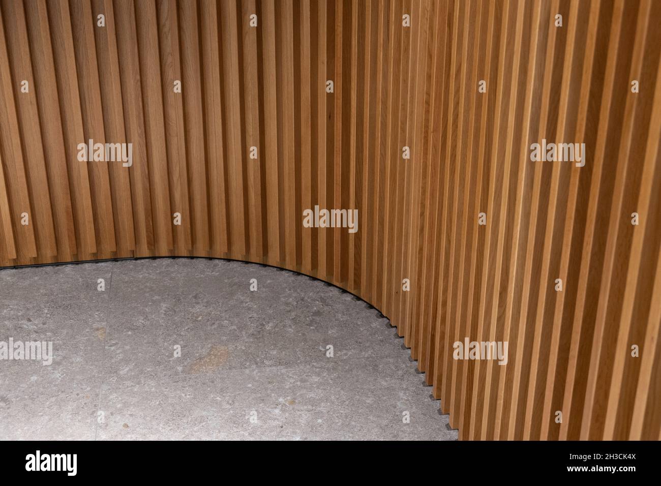 Combinación de pared de madera estriada curvilada y suelo de piedra. Panel texturizado de madera y baldosas de piedra gris. Detalle de diseño interior en esquina redonda. Foto de stock