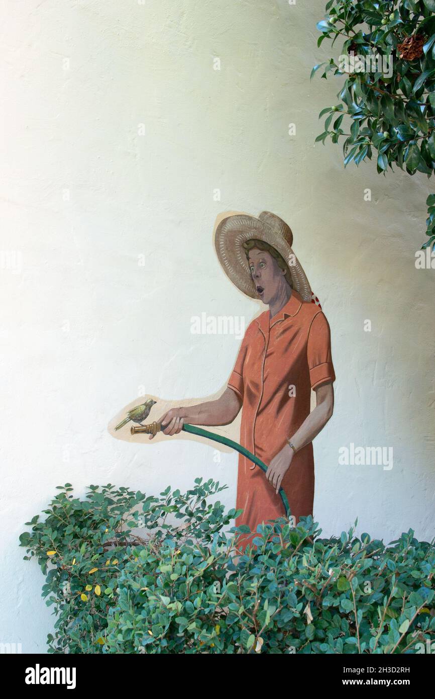 The Gardner aka Lady Watering, mural de Greg Brown mostrando a la señora riego real arbusto con pájaro en la manguera del jardín. 526 Waverley St, Palo Alto California Foto de stock