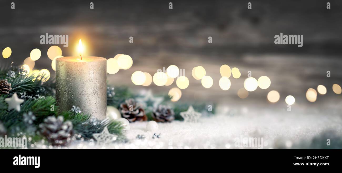 Decoración navideña con velas, luces, ramas de abeto y adornos en la nieve, formato panorámico Foto de stock