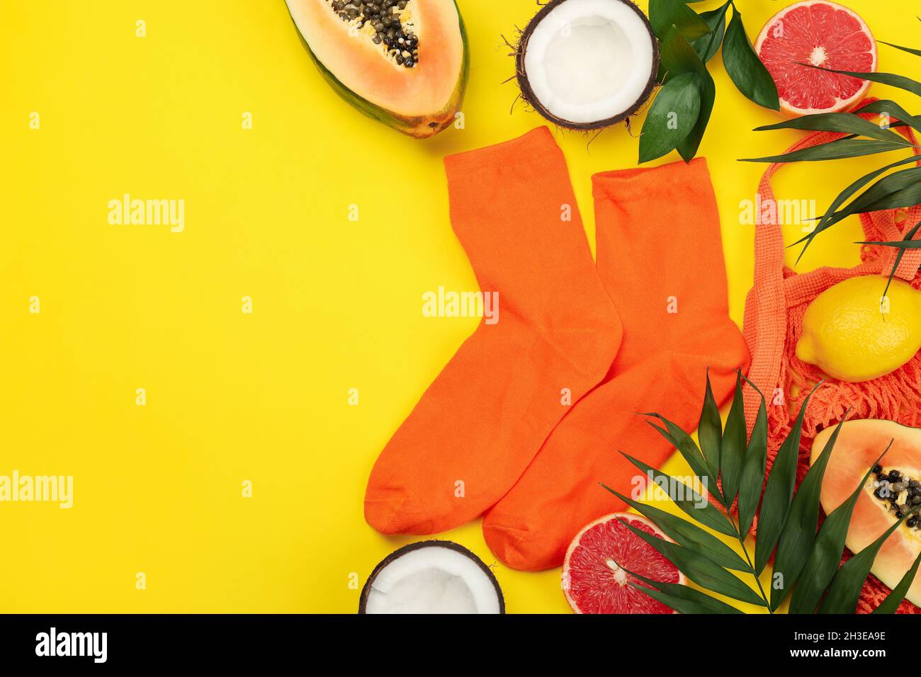 Calcetines de naranja y frutas exóticas sobre fondo amarillo Foto de stock
