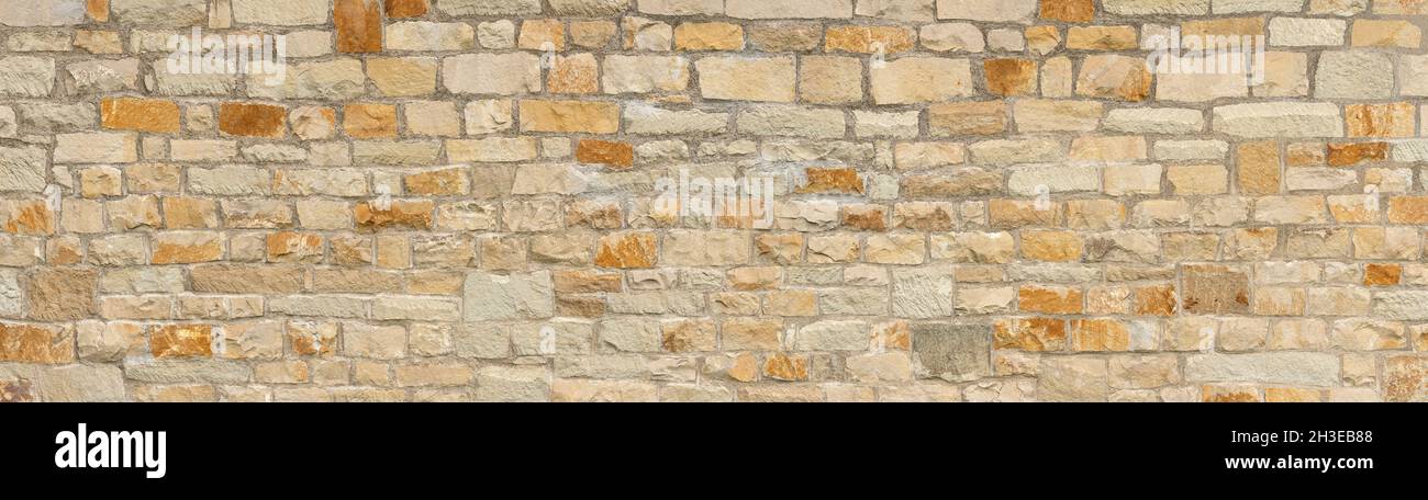 Pared panorámica de piedra hecha de viejas piedras naturales en beige, ocre y marrón Foto de stock