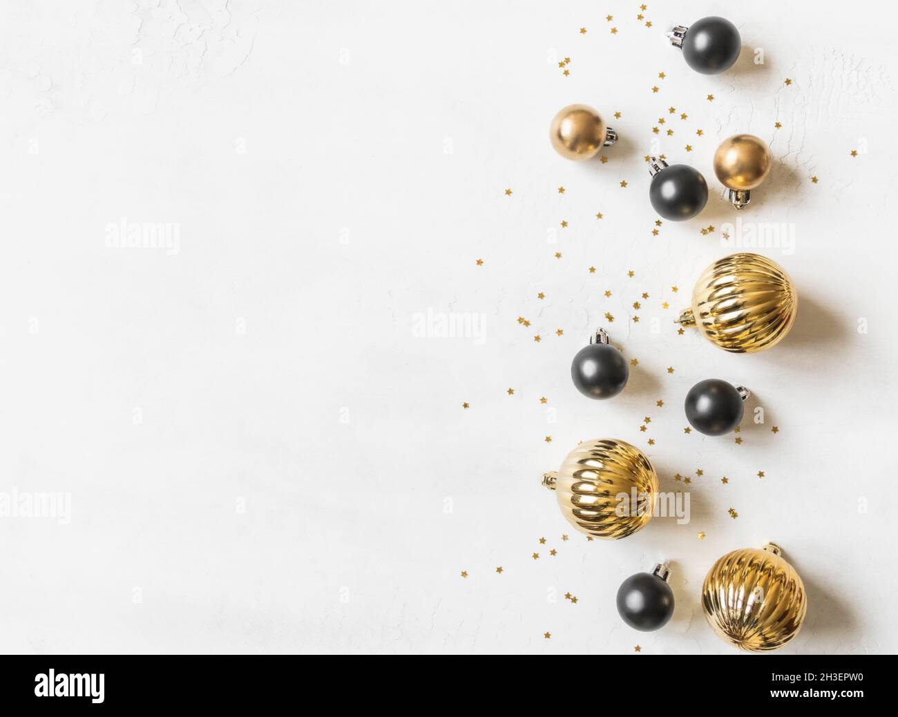 Tarjeta de felicitación - Feliz Año Nuevo y Feliz Navidad, estrellas de oro brillan y bolas de Navidad en negro y oro sobre fondo blanco texturizado. Unas vacaciones mínimas Foto de stock