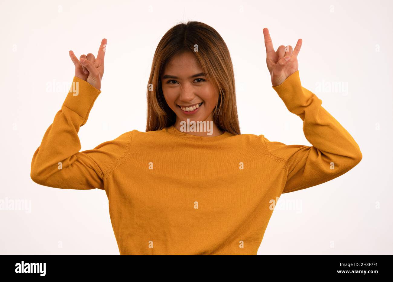 Joven atractiva chica asiática sonriendo con rock n roll pose en el estudio Foto de stock