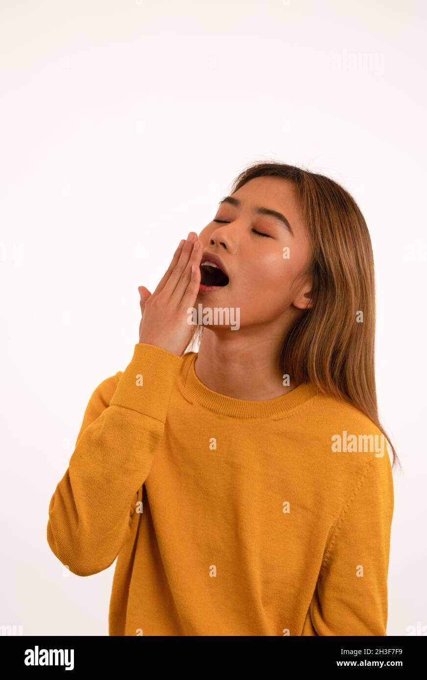 Joven atractiva y soñolienta chica asiática bostezando en el estudio Foto de stock