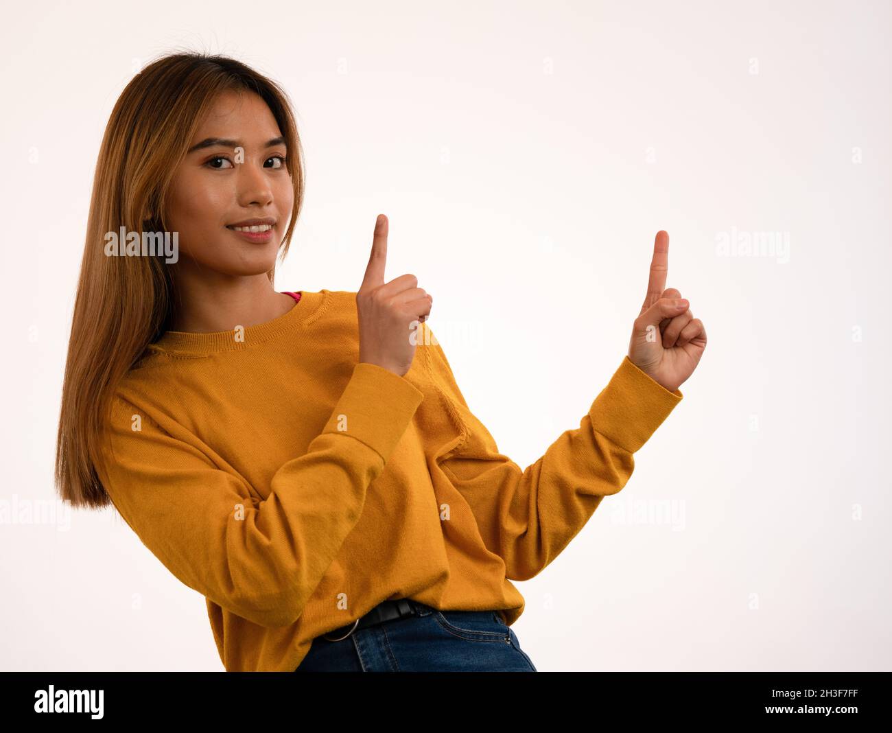 Joven atractiva chica asiática señalando el signo en el estudio Foto de stock