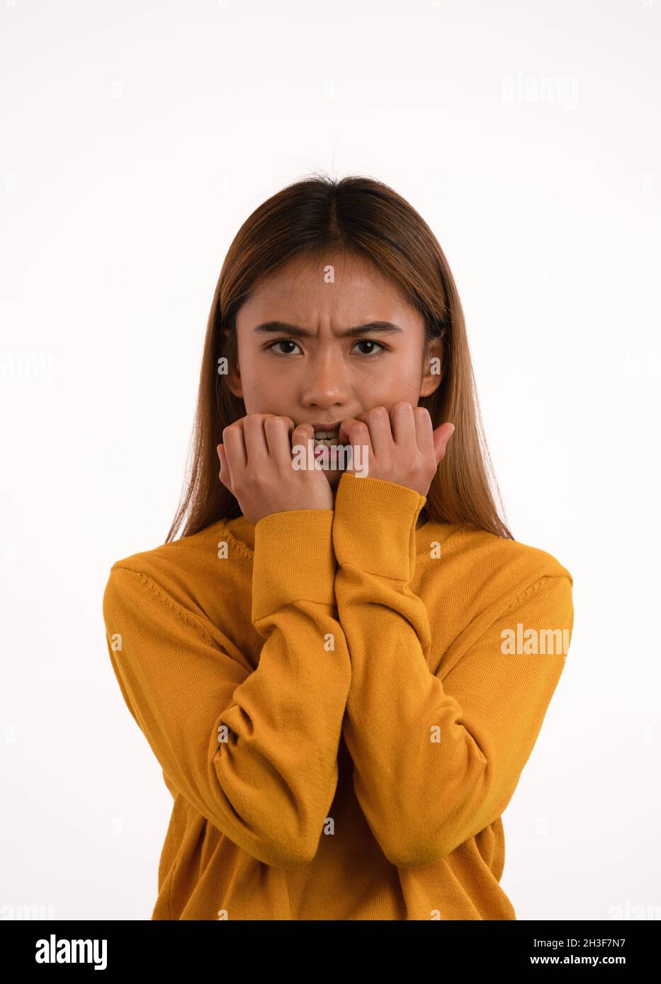 Joven atractiva nerviosa asustada chica asiática mordeando sus uñas en el estudio Foto de stock