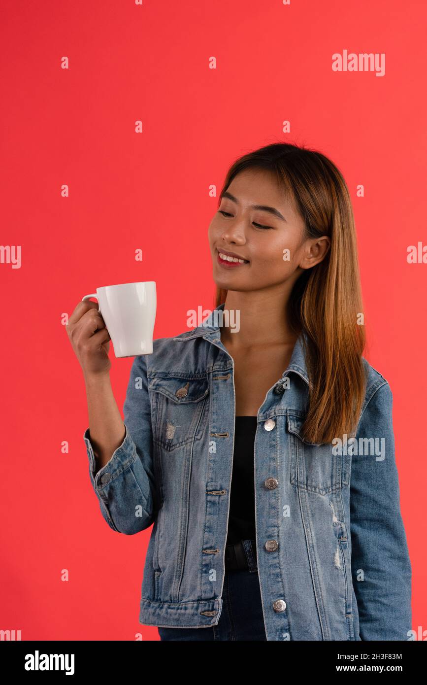 Joven atractivo asiático sonriendo mientras sostiene la taza Foto de stock