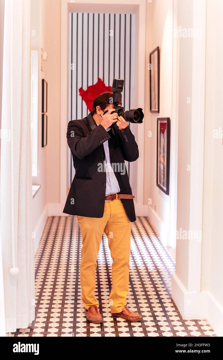 Joven toma de fotografía con cámara digital profesional, centrándose en la mano y la lente Foto de stock