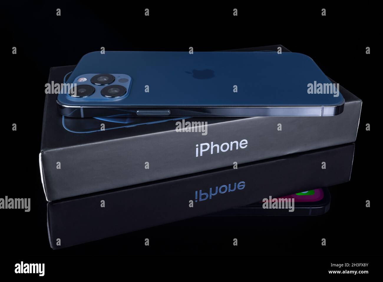 Galati, Rumania - 14 de octubre de 2021: Estudio de lanzamiento del nuevo Apple iPhone 12 Pro Max color azul, vista posterior con el logotipo de Apple. Aísle el fondo de vidrio negro Foto de stock