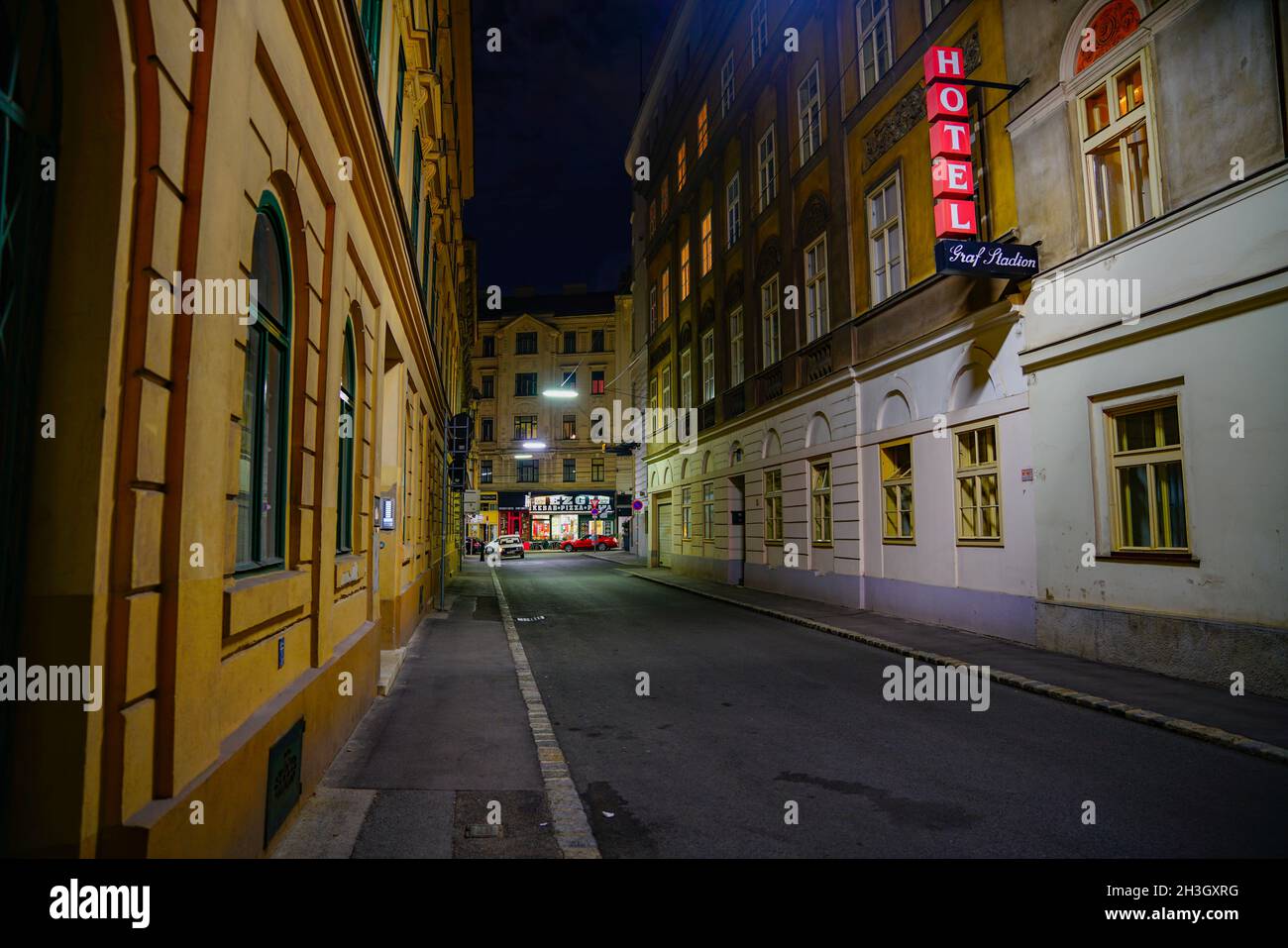 Viena, Austria - 5 2017 de septiembre; vista a lo largo del distrito de negocios urbano, calle estrecha convergiendo hacia la intersección con la señal de hotel iluminada en rojo Foto de stock