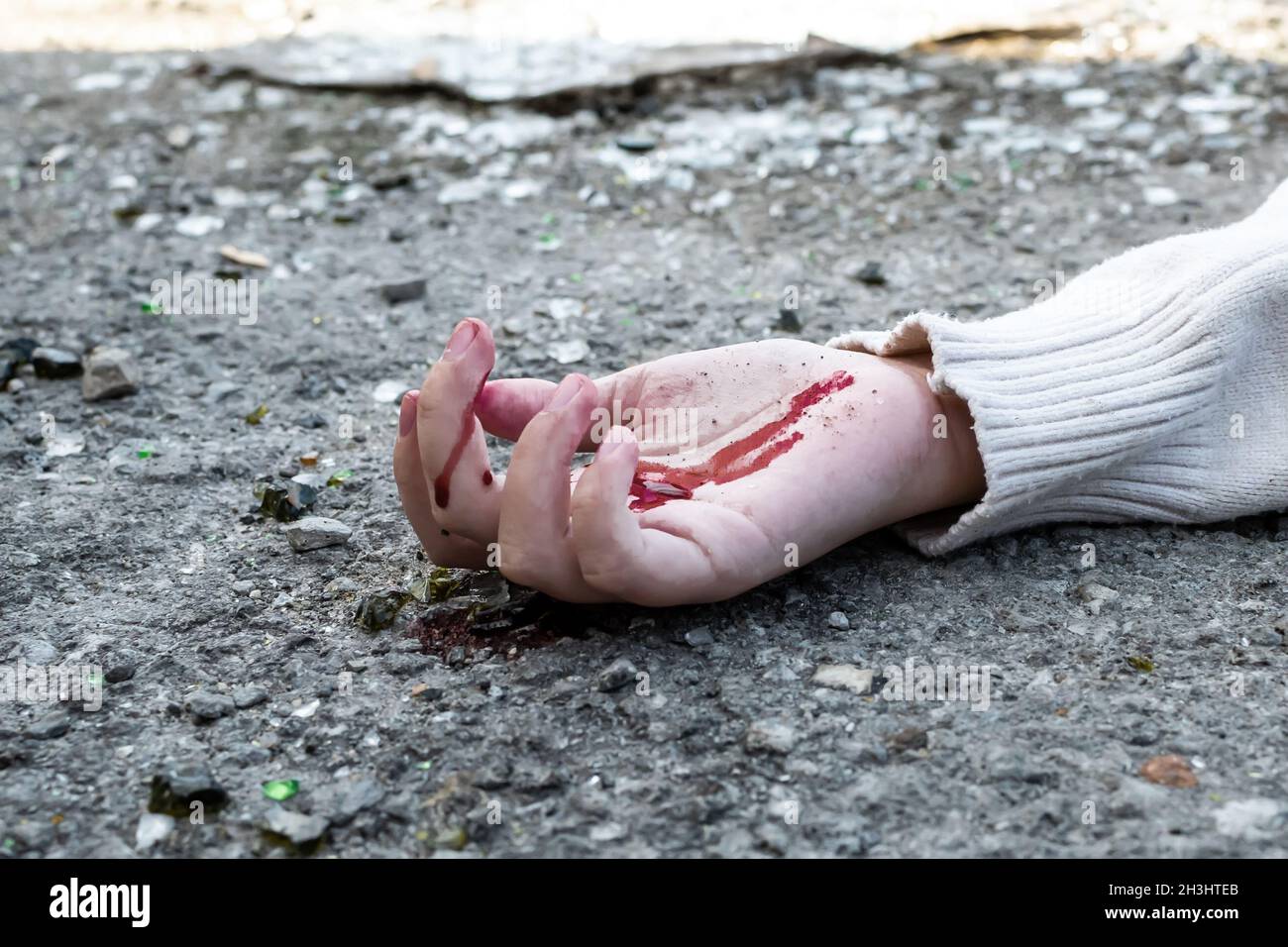 la mano de un hombre en sangre se encuentra en el asfalto de la carretera después de un accidente automovilístico. Foto de stock
