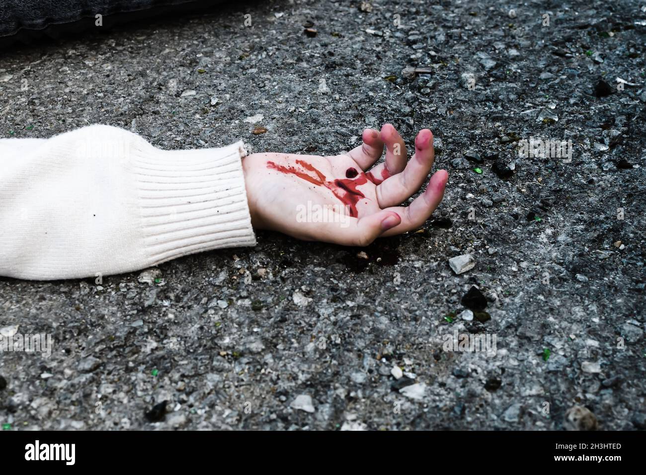 la mano de un hombre está cubierta de sangre sobre el asfalto de la carretera. Foto de stock