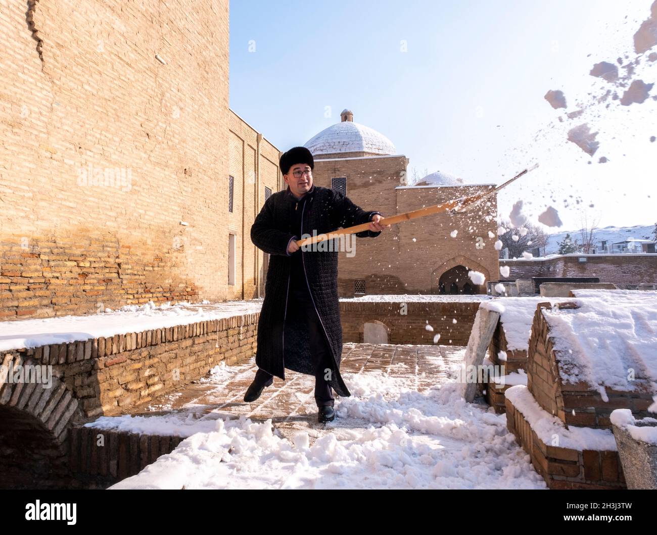Un asistente despeja la nieve del camino de la necrópolis de Shahi-Zinda en Samarcanda, Uzbekistán Foto de stock