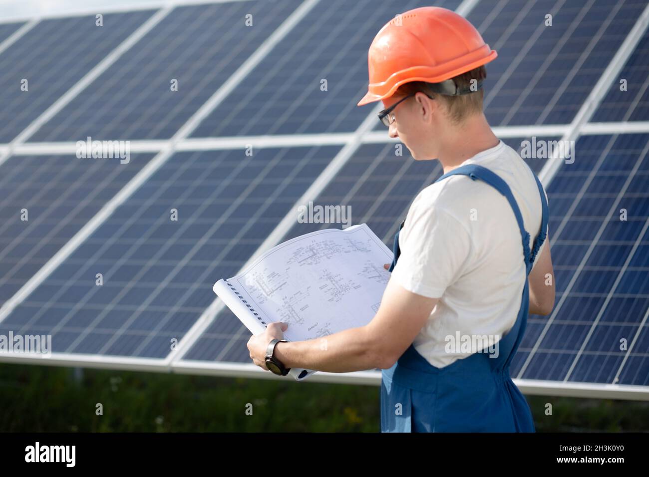 Joven trabajador en general buscando en dibujos a la estación de energía solar. Foto de stock