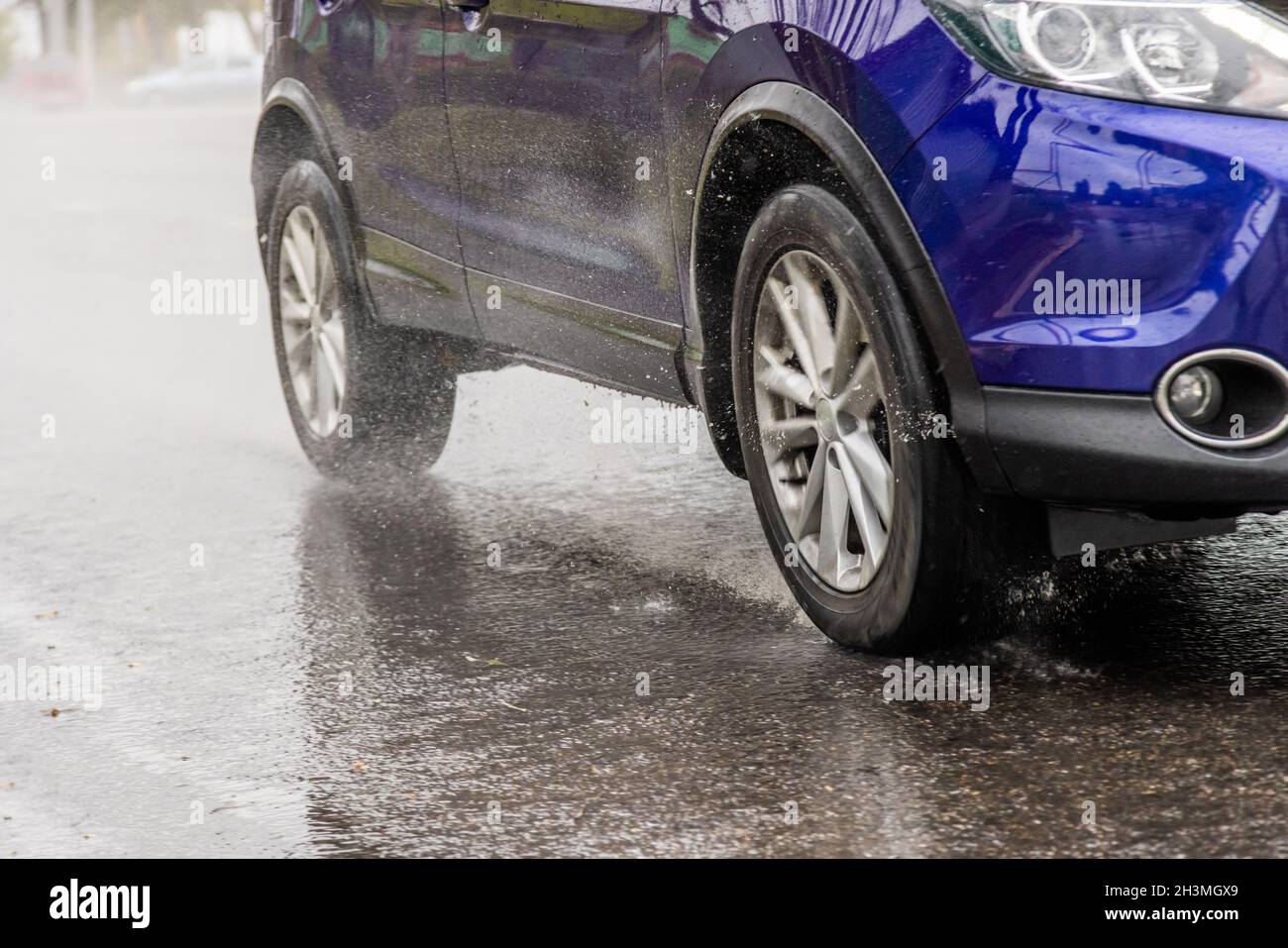 el suv azul se apresura a la carretera húmeda de asfalto otoñal Foto de stock