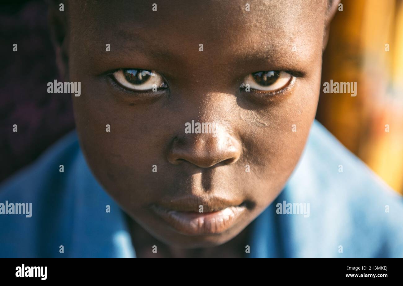 TRIBU BOYA, SUDÁN DEL SUR - 10 DE MARZO de 2020: Niño envuelto en tela azul mirando la cámara mientras vive en la aldea de Boya Tribe en So Foto de stock
