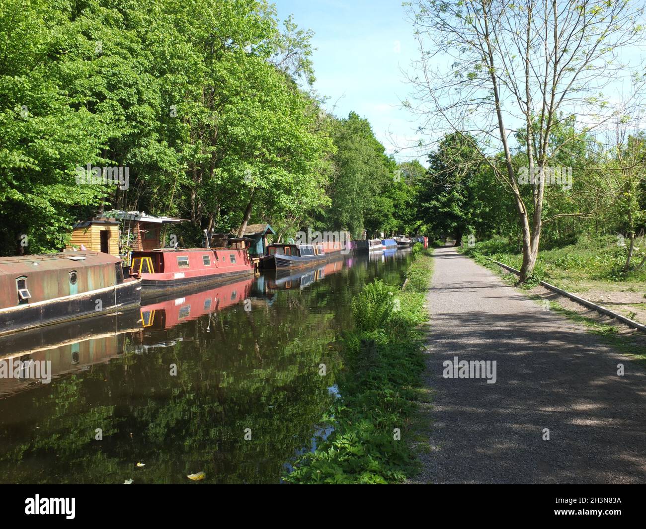 Barcos antiguos del canal amarrados en el canal rochdale cerca del puente hebden rodeado de árboles bajo la luz del sol en verano Foto de stock
