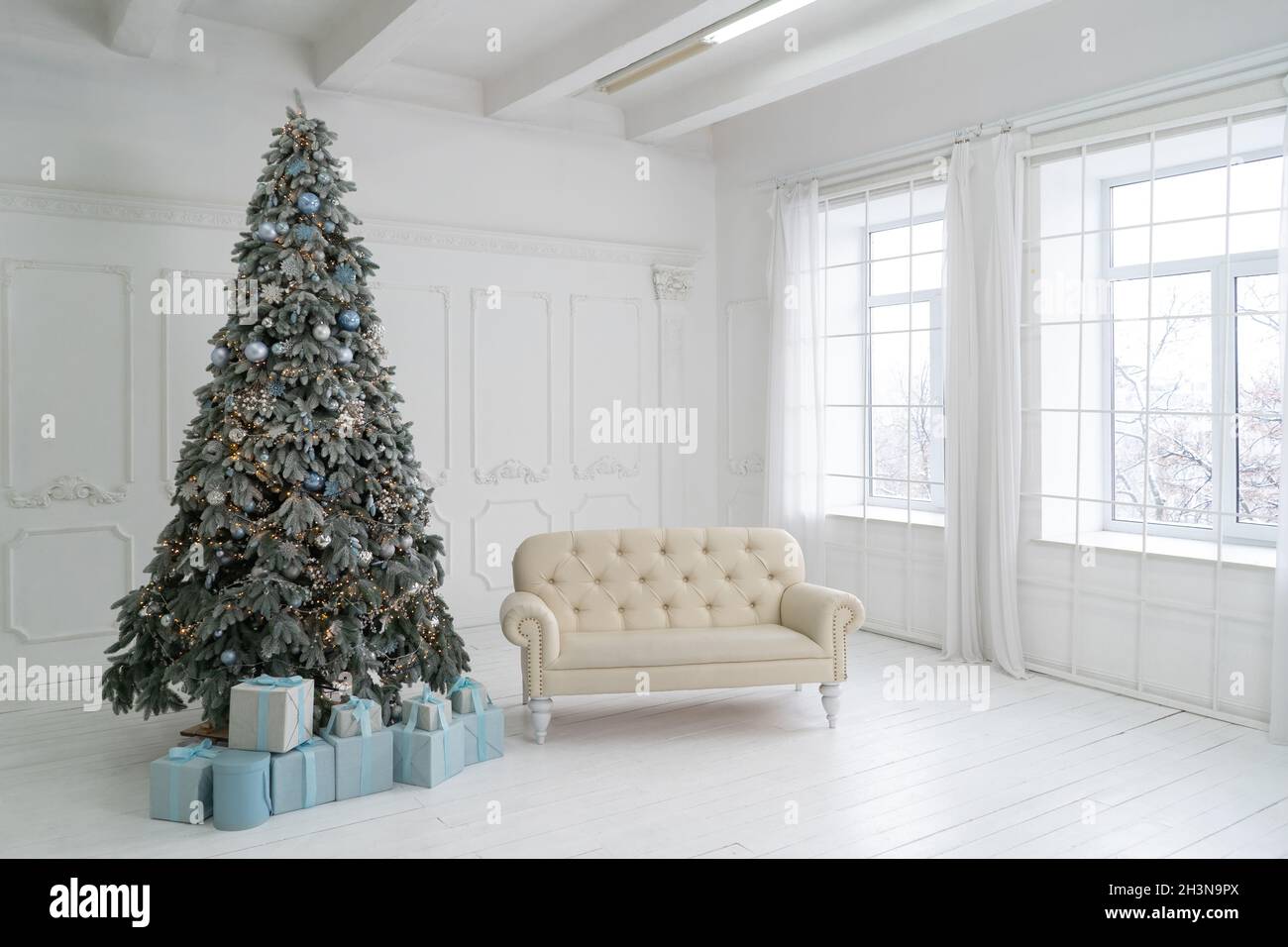 Interior de estudio de Año Nuevo. El árbol de Navidad está decorado con  globos, con regalos de Navidad debajo. Bajo el hay un sofá blanco  Fotografía de stock - Alamy