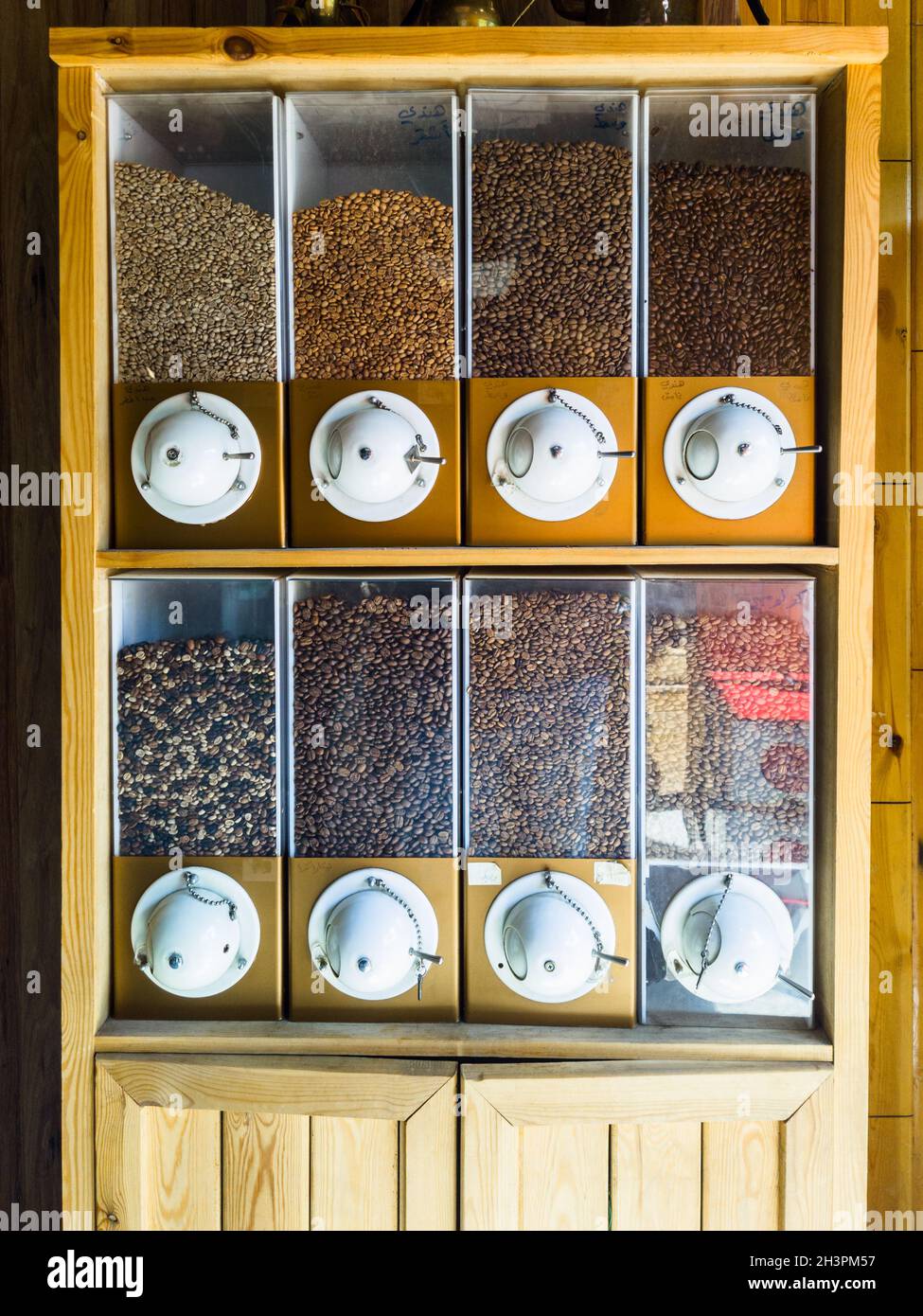 Vista de cerca del armario de granos de café con varios tipos y orígenes de granos de café en la pantalla para los clientes Foto de stock