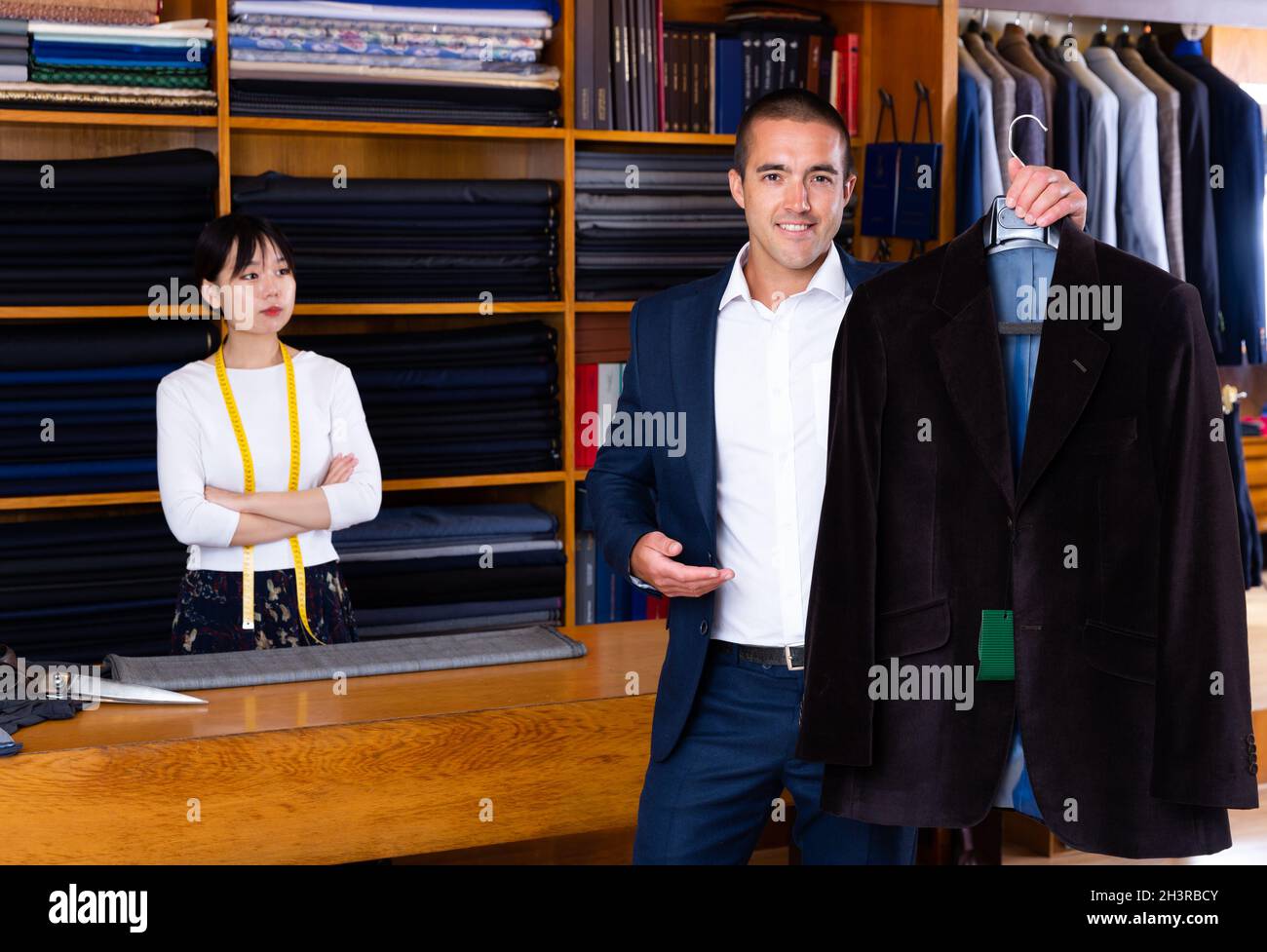 Hombre feliz sosteniendo chaqueta clásica en la tienda de ropa Fotografía  de stock - Alamy