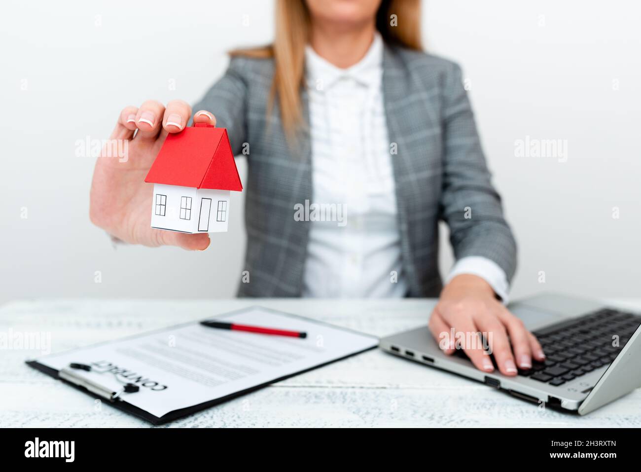 Una dama que sostiene el hogar en el conjunto del negocio que presenta los cálculos posibles para poseer las propiedades inmobiliarias. Firma de un nuevo contrato Orinsurance Foto de stock