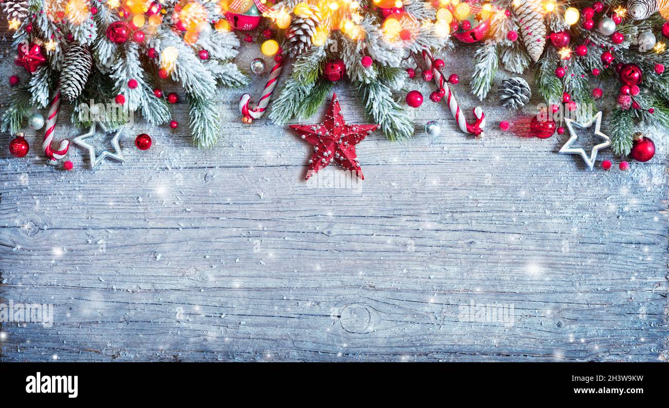 Adorno de Navidad con ramas de abeto y nieve en plancha de madera azul Foto de stock