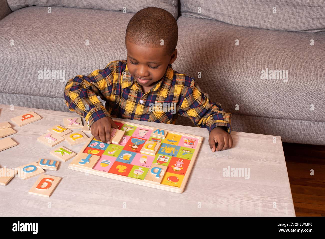 Niño de edad preescolar en casa jugando con rompecabezas del alfabeto Foto de stock