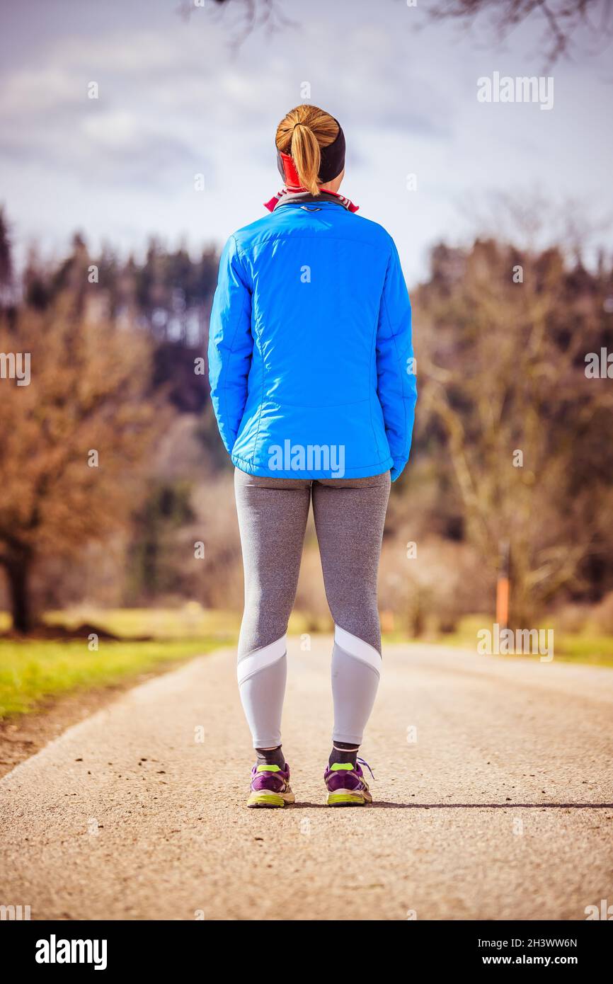 Mujer joven en ropa deportiva en un camino, campo: Esperando para comenzar  el entrenamiento Fotografía de stock - Alamy