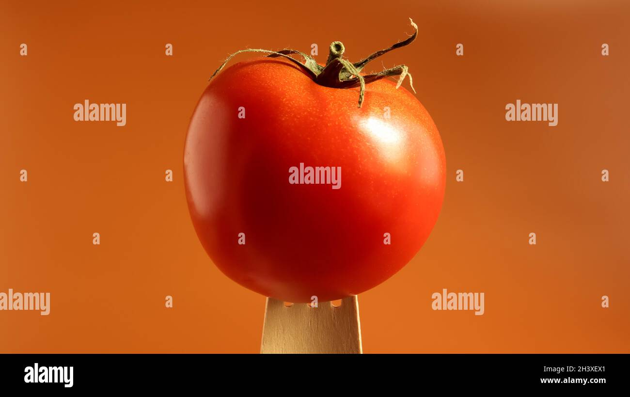 Un solo sabroso tomate rojo en un tenedor de madera. Porque la idea de la cuestión de los alimentos es espacio abierto. jugosa baya multi-anidada. Una o anual Foto de stock