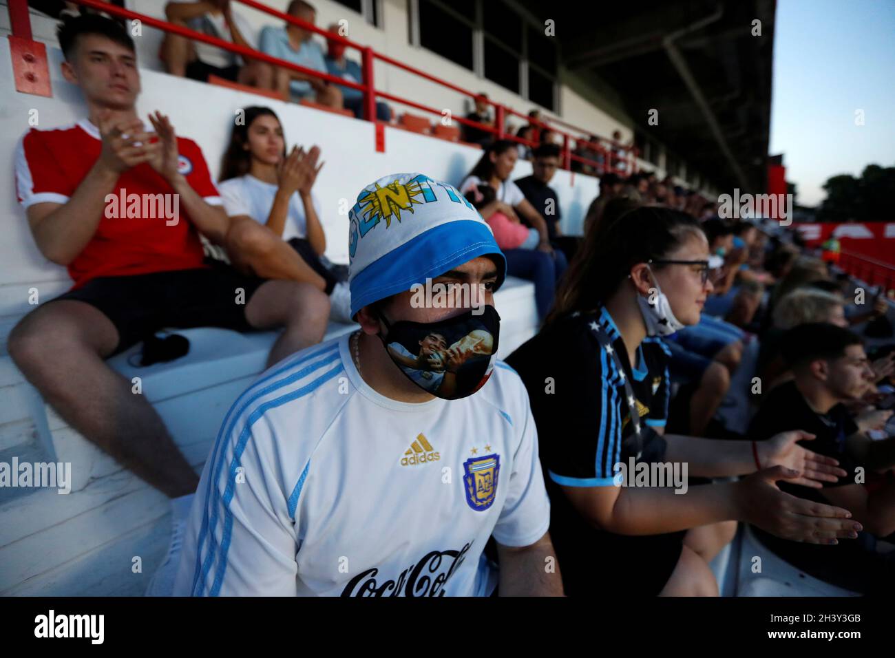 Un hombre con una máscara que representa a Diego Armando Maradona, leyenda  del fútbol, mira hacia el estadio Diego Maradona, antes de una celebración  que marca la fecha de nacimiento de Maradona