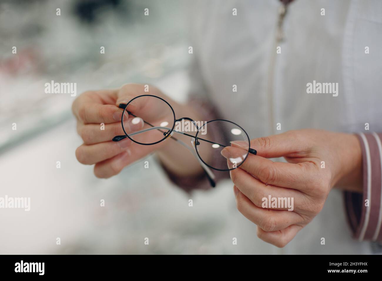 Mujer mano con lentes de gafas de moda. Anteojos dioptrías transparentes Foto de stock