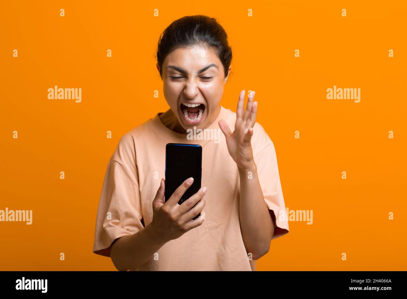 Retrato de mujer india gritando con teléfono móvil. Gritos y limpieza de redes sociales cansado trabajo duro. Foto de stock