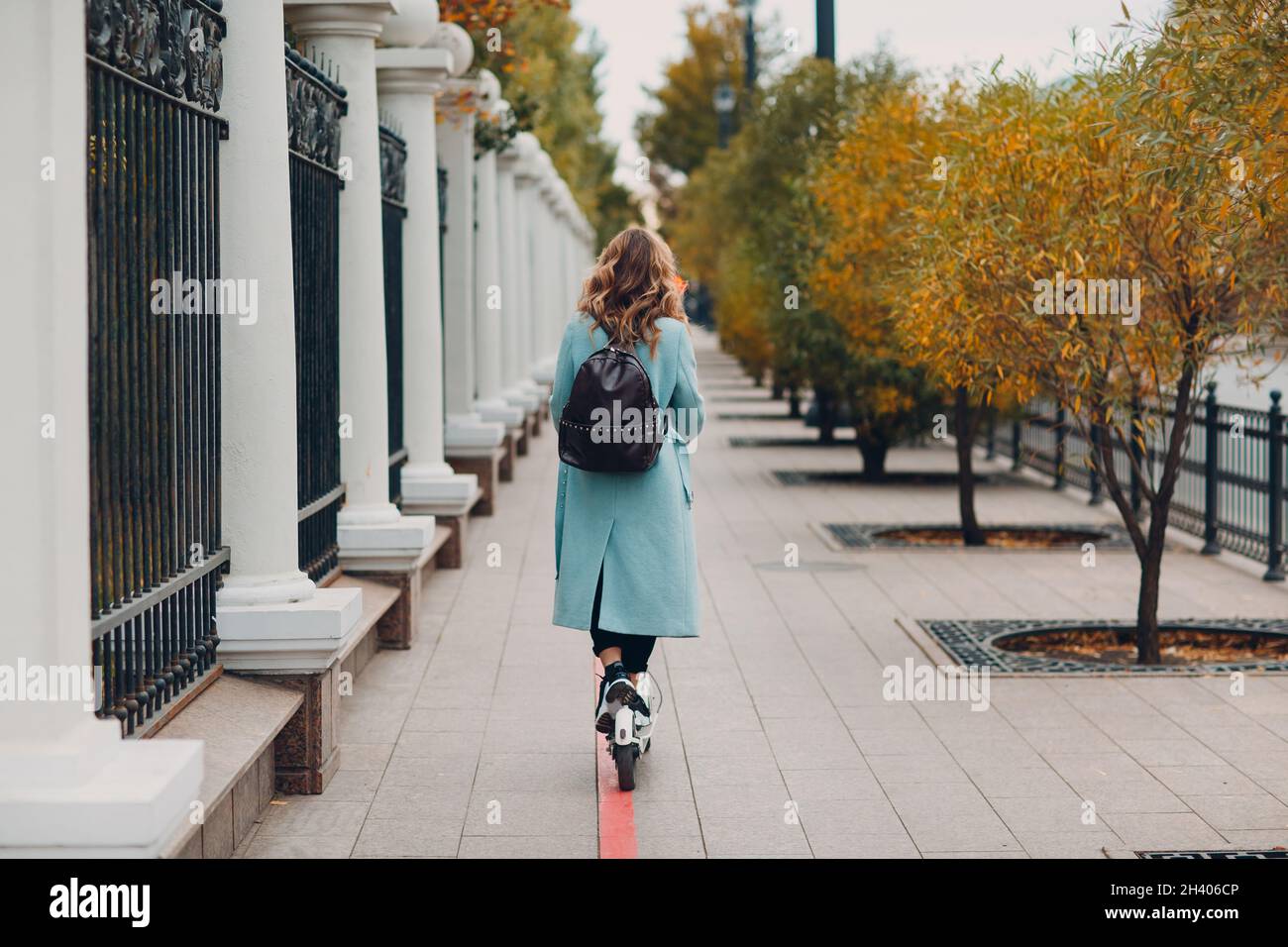 Mujer joven con scooter eléctrico con abrigo azul en el carril de  bicicletas de la ciudad Fotografía de stock - Alamy