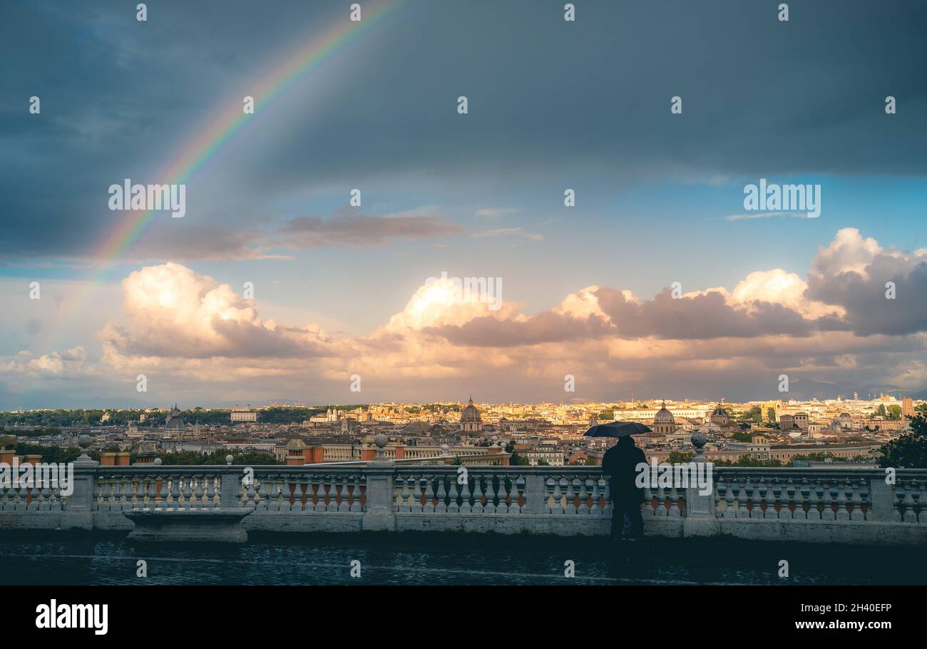 hombre con paraguas. Arco iris sobre la ciudad de Roma Foto de stock