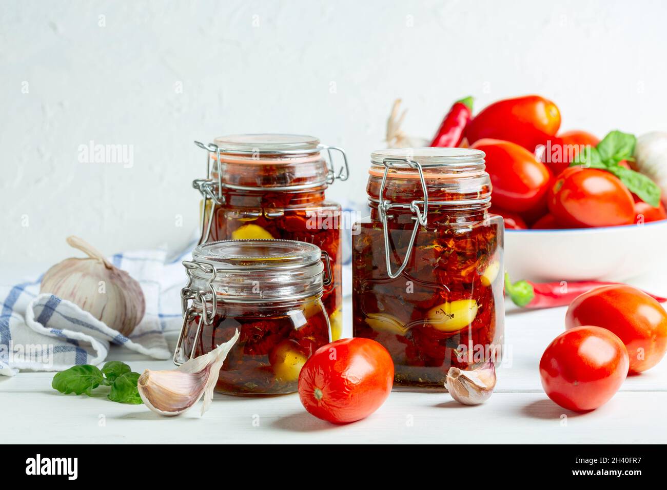 Tomates secos caseros con ajo y aceite de oliva en tarros de vidrio. Foto de stock