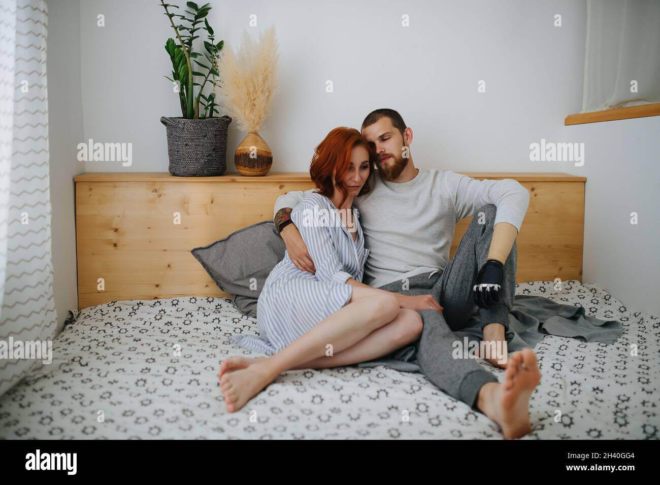 Cansada pareja de treinta años reasando en la cama, hombre abrazando a una  mujer. Tiene una mano protésica biónica Fotografía de stock - Alamy