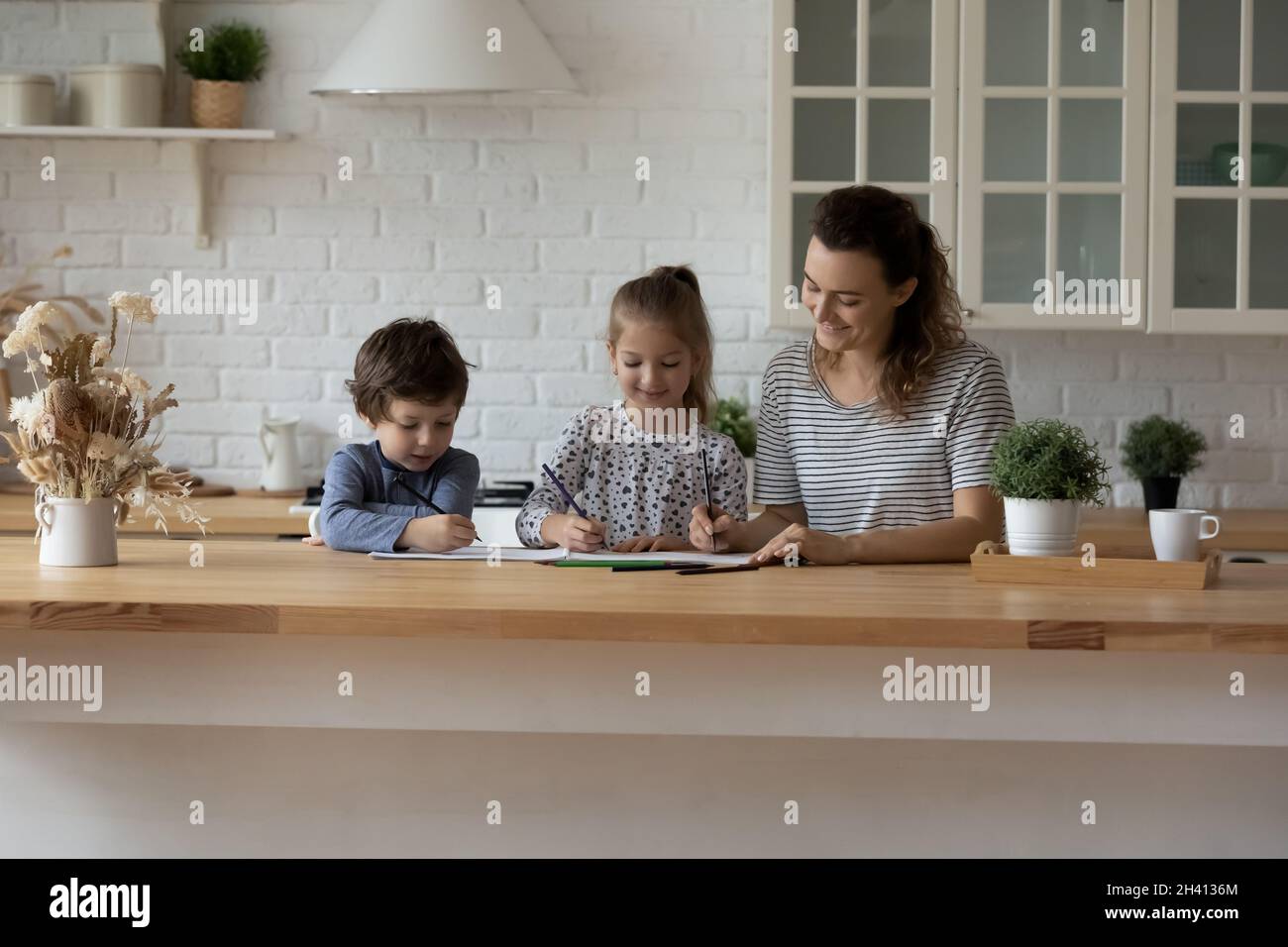 Feliz lindo niños dibujando en un álbum de papel con mamá. Foto de stock