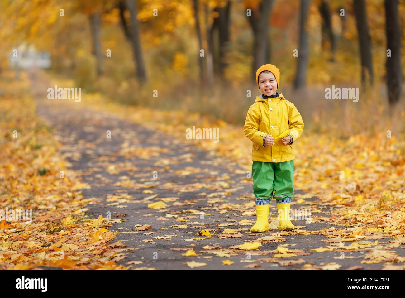 Niño Con Paraguas De Colores, Vestido Con Capa Impermeable Amarilla Y Botas  De Pie Bajo La Lluvia. Niño Caminando En La Ducha De Otoño. Fotos,  retratos, imágenes y fotografía de archivo libres