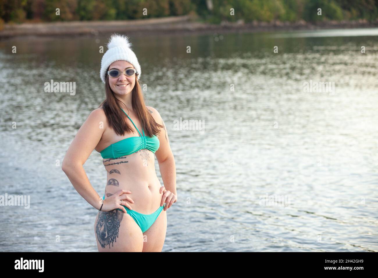Una mujer joven que lleva un bikini de pie cerca del borde del mar con un  sombrero de lana listo para nadar en invierno Fotografía de stock - Alamy