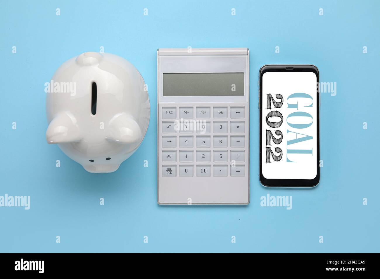 Calculadora con teléfono móvil y banco piggy sobre fondo de color.  Objetivos del Año Nuevo 2022 Fotografía de stock - Alamy