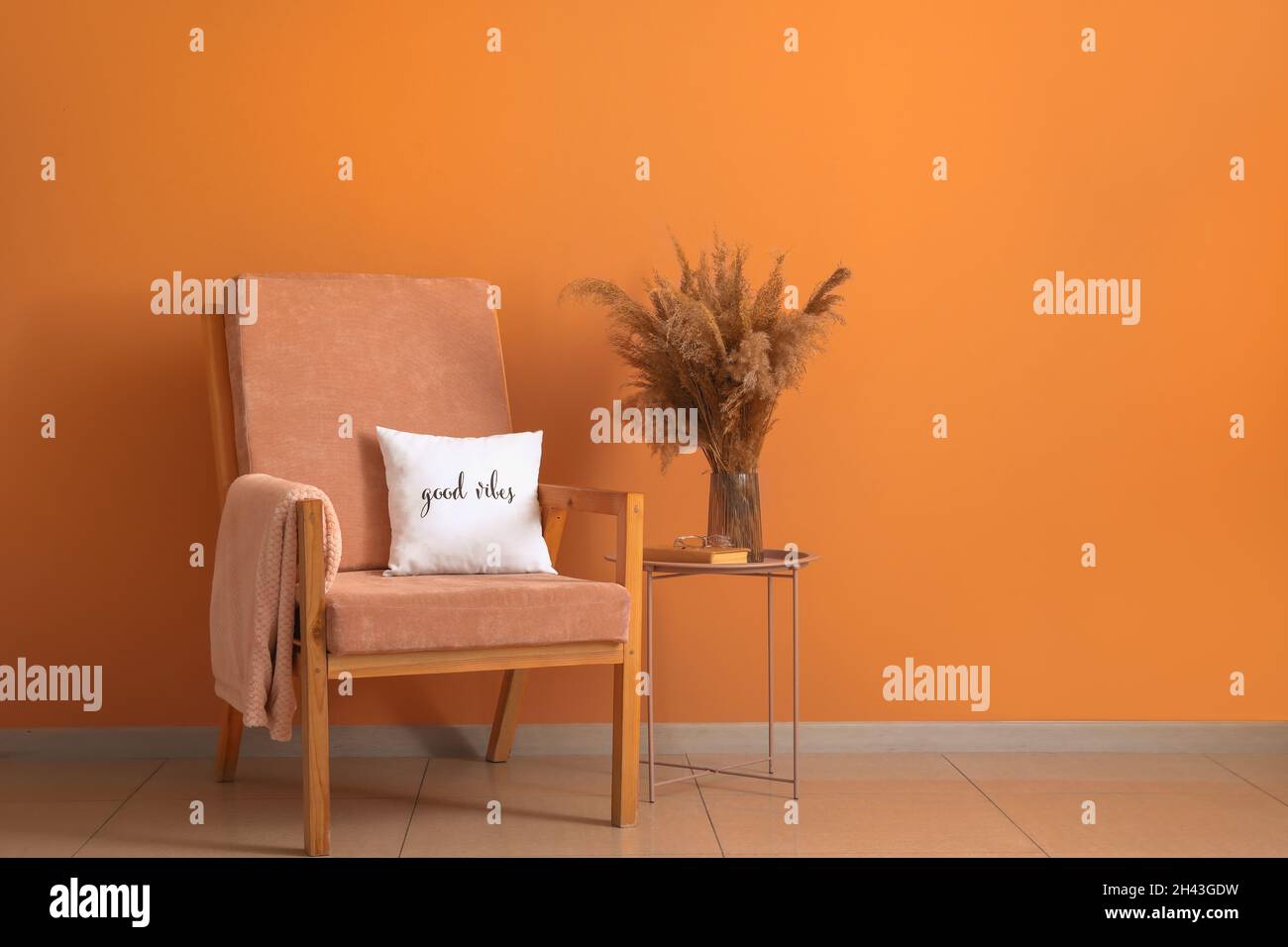 Elegante sillón y mesa con decoración floral cerca de la pared naranja  Fotografía de stock - Alamy