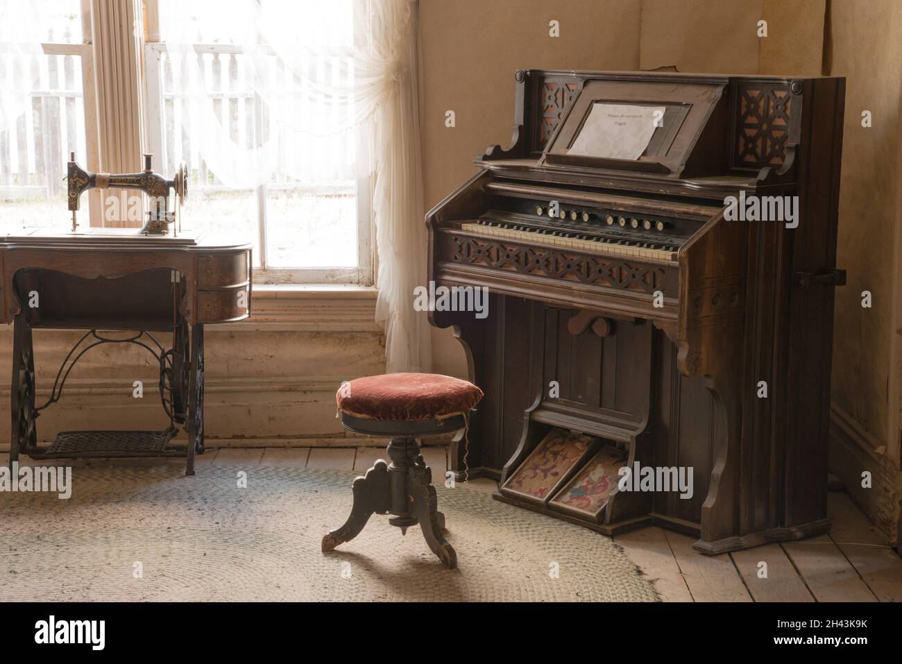 Un viejo pianista y máquina de coser en exposición en la Casa del Dr. Ryburn en la ciudad fantasma de Bannack, MT, Estados Unidos Foto de stock