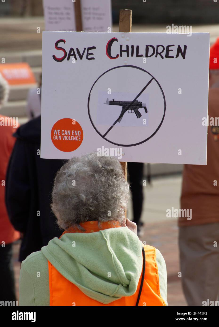 Una mujer mayor tiene una señal en una manifestación de protesta con armas de fuego que dice 'Save Children. Podemos poner fin a la violencia con armas de fuego.' Foto de stock