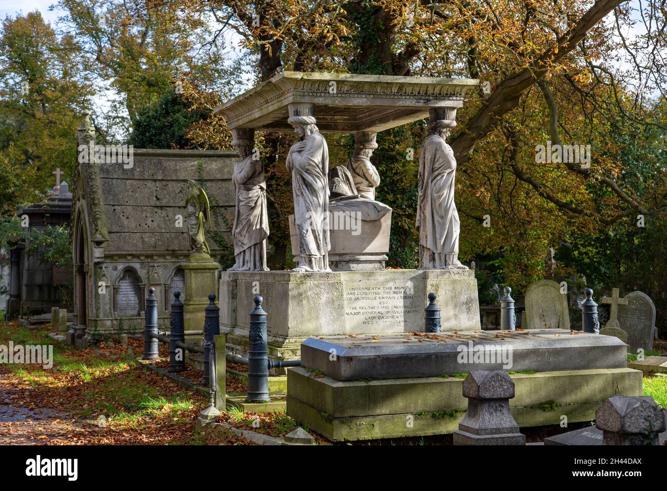 Monumentos funerarios de piedra de principios del siglo XIX, uno de ellos con caryatids en el cementerio verde de Kensal bajo el sol de otoño Foto de stock