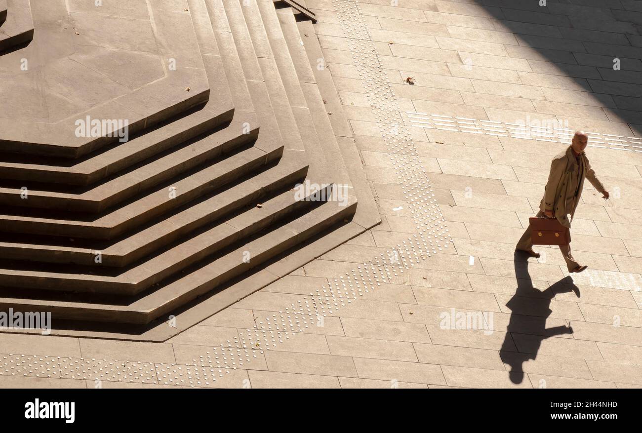 Belgrado, Serbia - 25 de octubre de 2020: Un hombre calvo en traje y abrigo que lleva maletín caminando solo por las enormes escaleras públicas, vista de alto ángulo en sí Foto de stock
