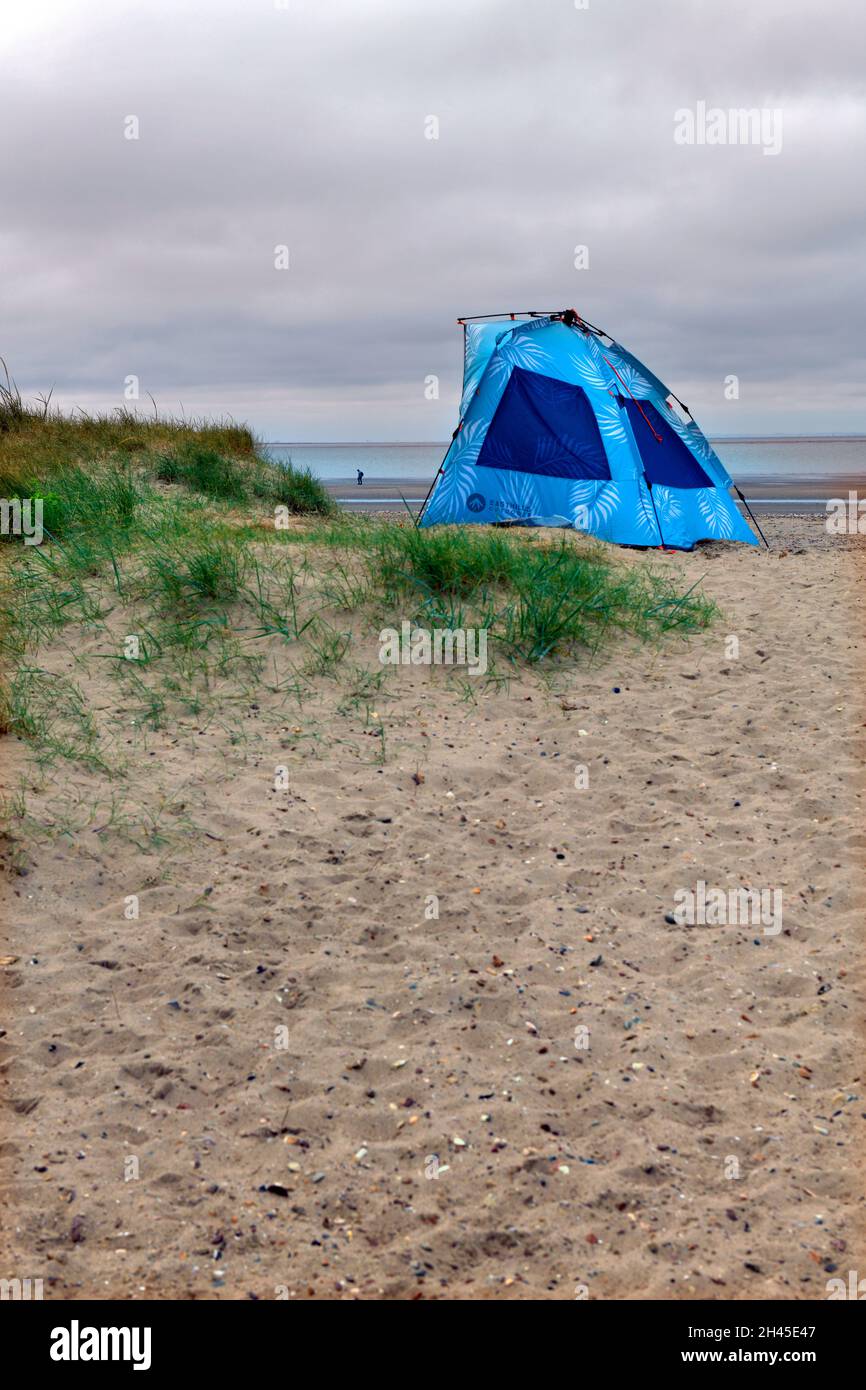 solitaria pequeña figura y pop up refugio de playa en el beac en holme al lado del mar al norte de norfolk inglaterra Foto de stock
