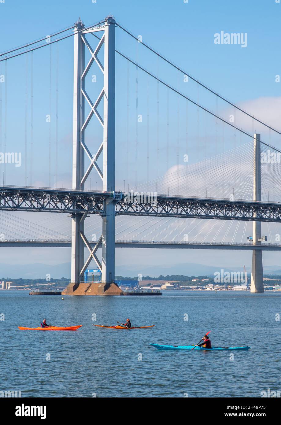 South Queensferry, Edimburgo, Escocia 7th de septiembre de 2021 - Tres kayaks que pasan bajo los puentes de Forth Road en un día soleado con cielo despejado. Foto de stock