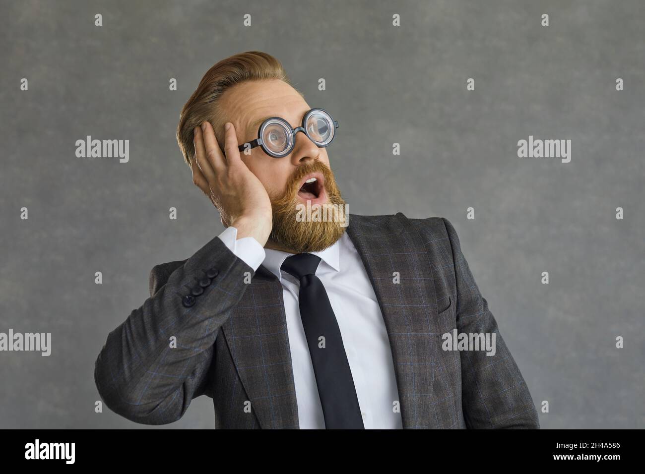 Divertido hombre de negocios sorprendido en gafas redondas mirando hacia fuera con la expresión de la cara conmocionada Foto de stock