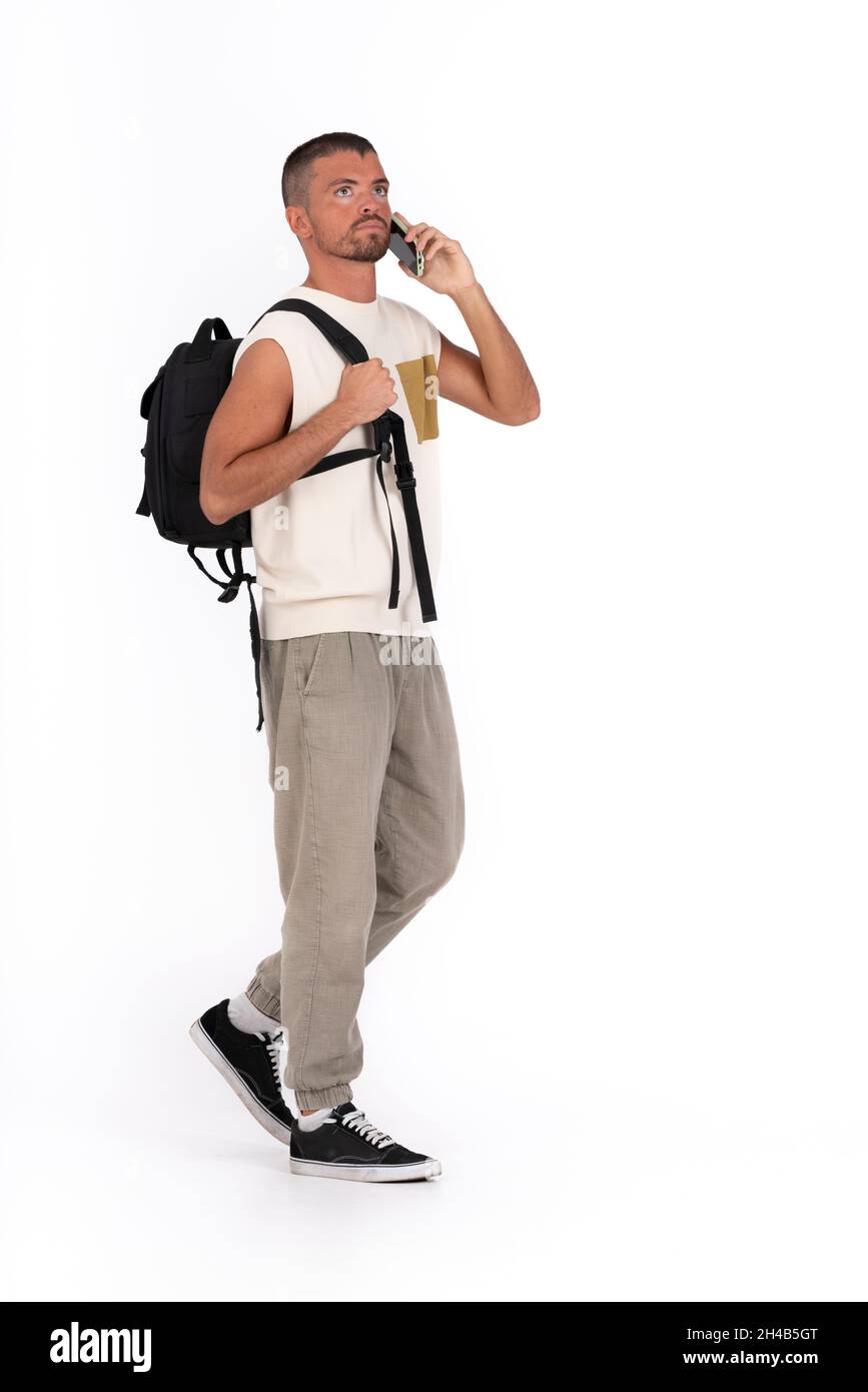 Hombre joven llevando una mochila sobre un fondo blanco y hablando por  teléfono Fotografía de stock - Alamy