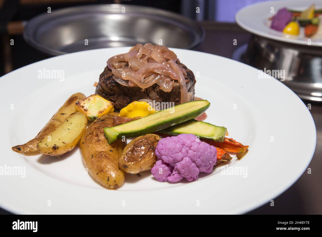 En un evento se sirve un plato de cena con bistec, patatas a la parrilla y verduras asadas. Foto de stock